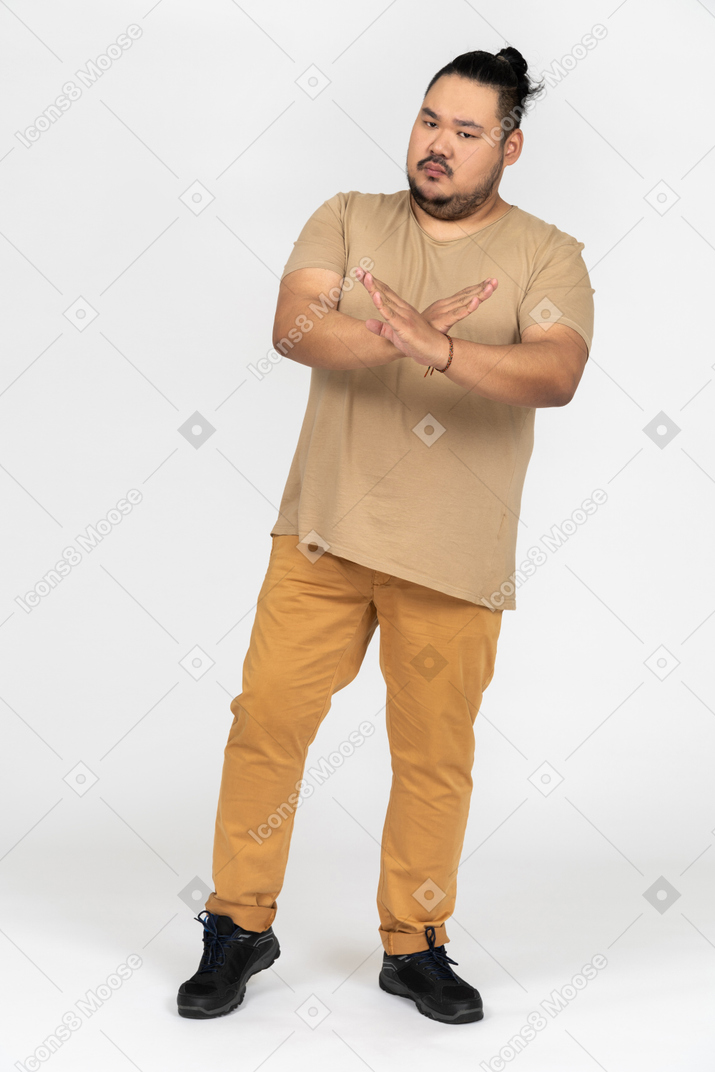 Young asian man crossing his hands making a stop gesture