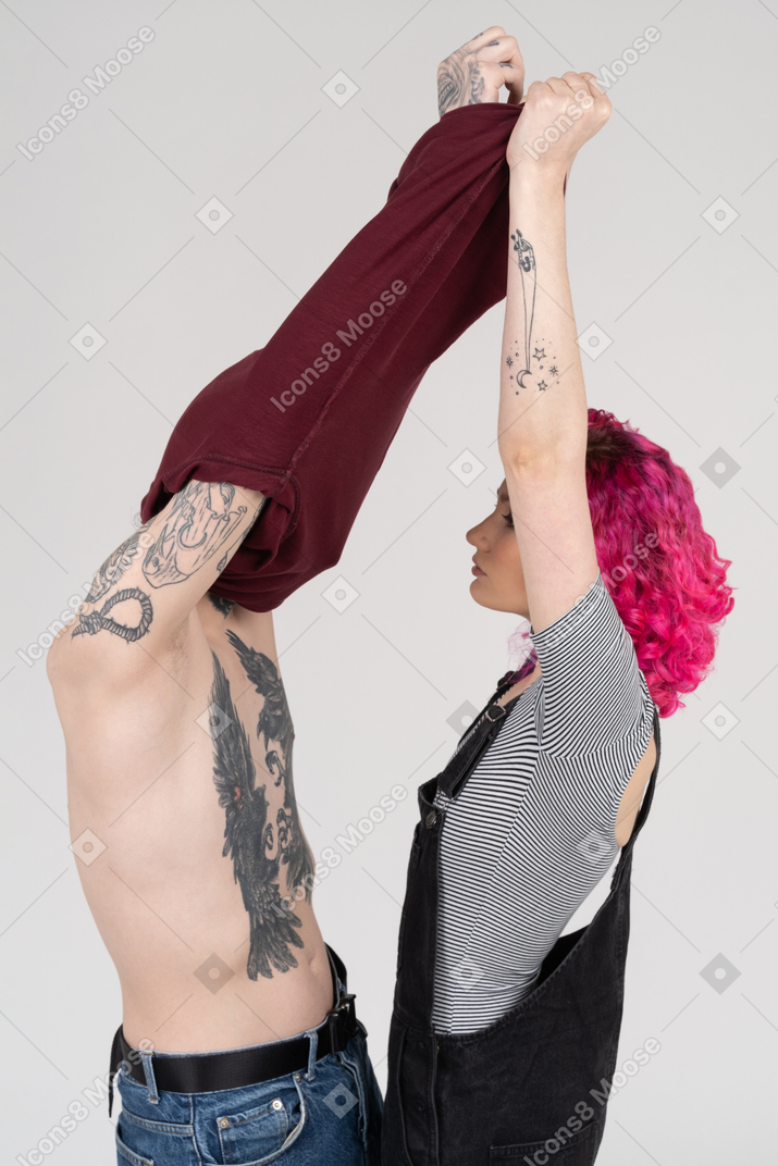 Pink-haired female takes t-shirt off her boyfriend