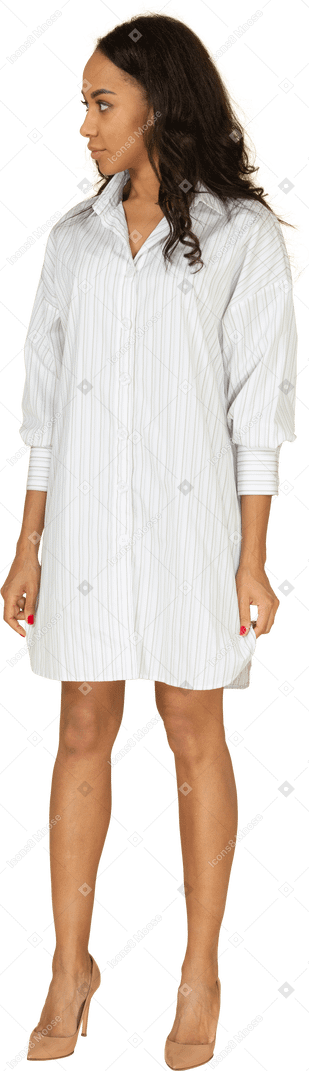 Vista de tres cuartos de una mujer joven de piel oscura confiada en vestido blanco