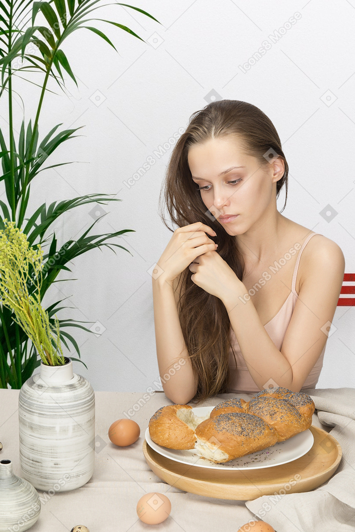 沉思的年轻女子在桌上的面包