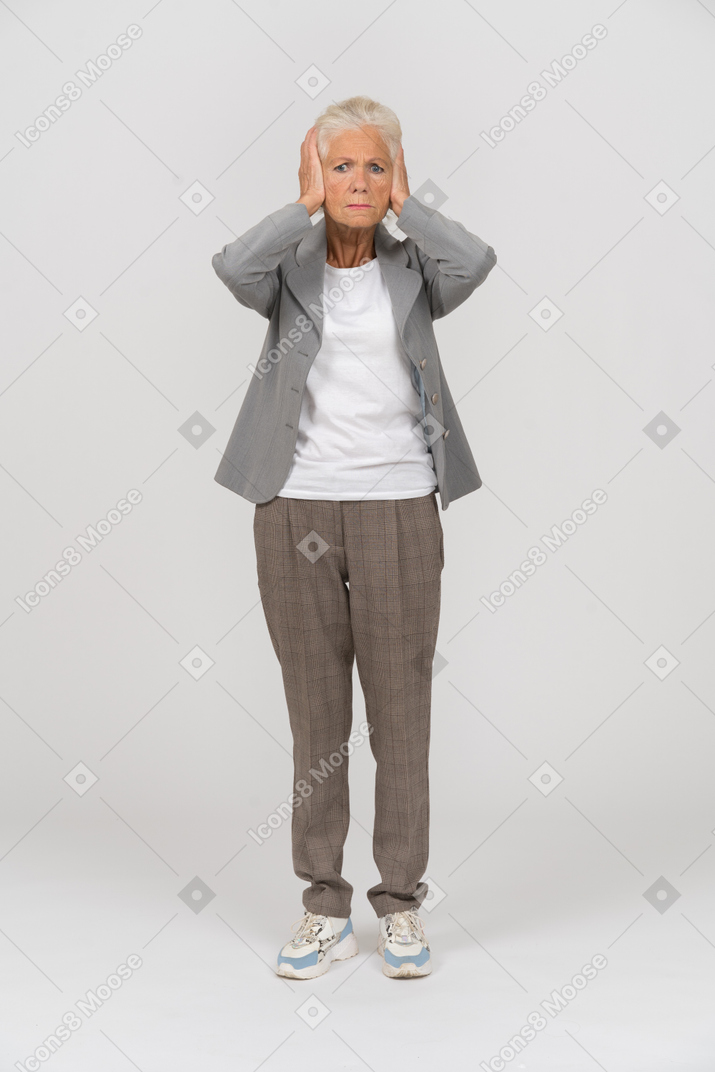 一位身穿西装、用手捂住耳朵的老妇人的前视图