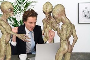 Hombre en la computadora portátil rodeado de extraterrestres