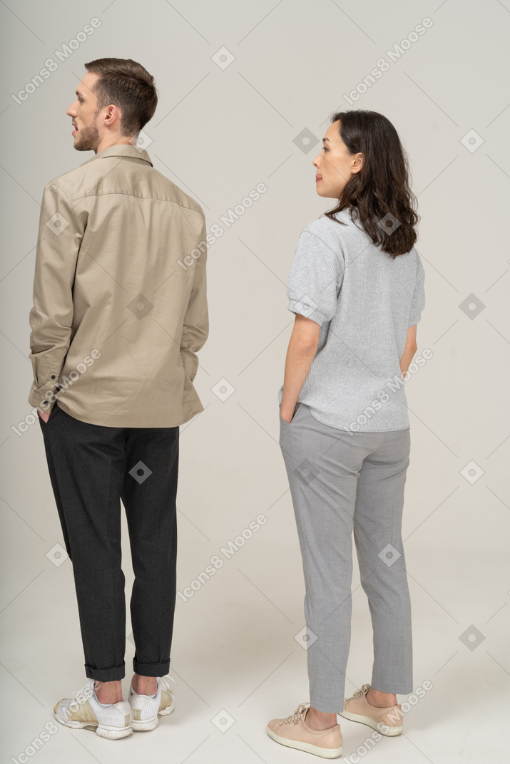 Вид сзади на стоящую молодую пару в три четверти