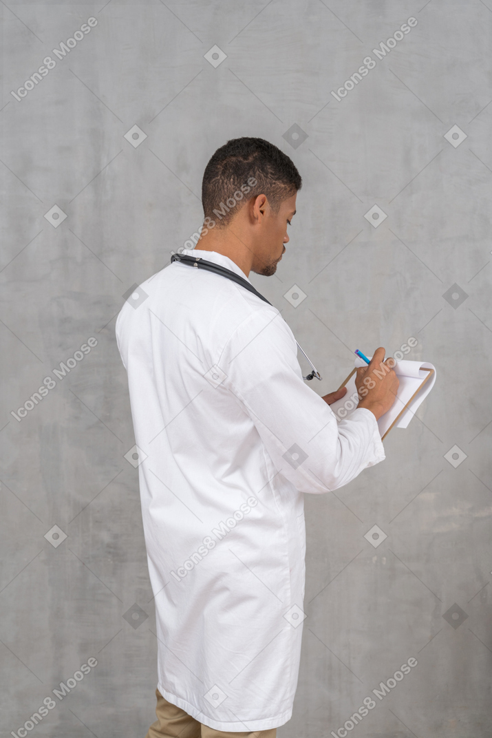 Vista posterior del joven médico tomando notas