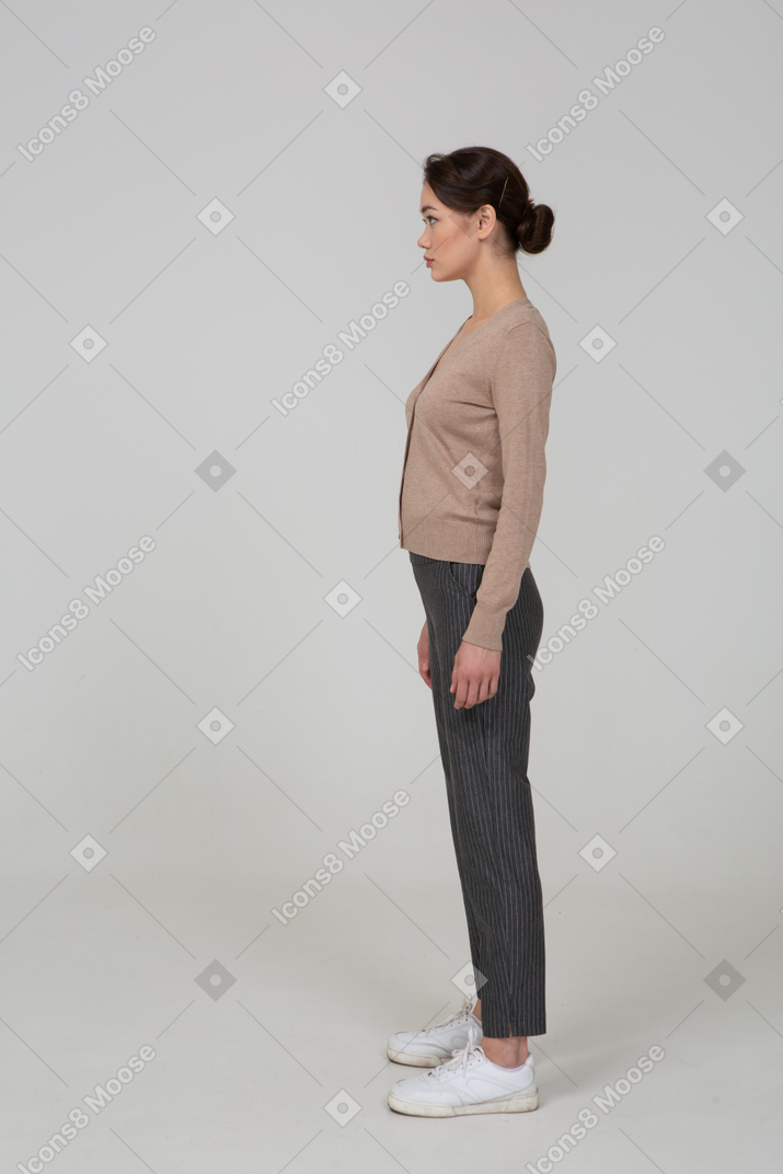 Vista laterale di una giovane donna in piedi ancora in pullover e pantaloni