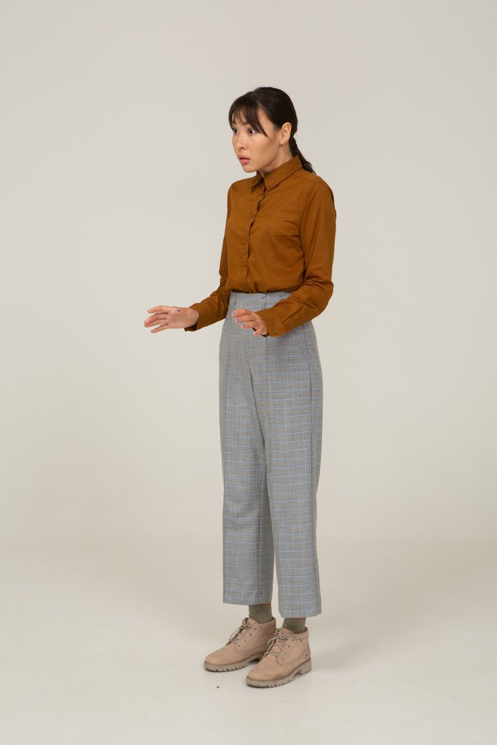 Three-quarter view of a young asian female in breeches and blouse raising her hands