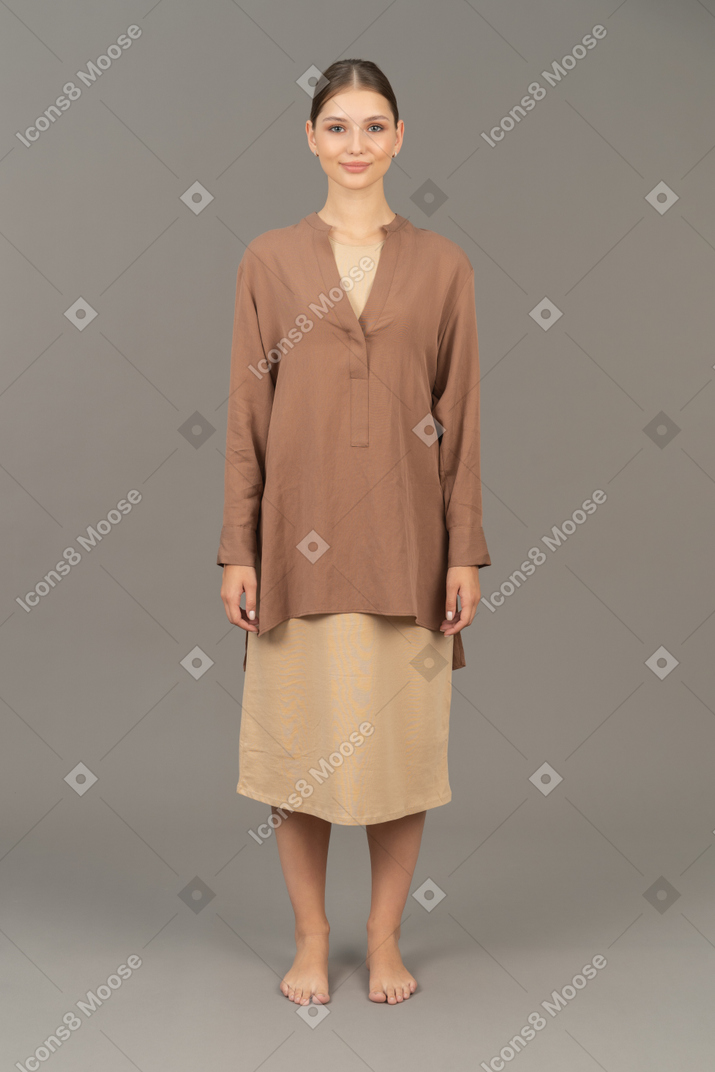 Vista frontale di una giovane donna in piedi a piedi nudi e sorridente