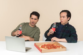 Blown away interracial friends eating junk food and watching movie on laptop