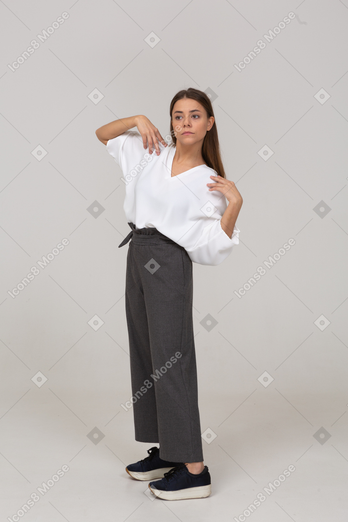 Three-quarter view of a young lady in office clothing touching her shoulders