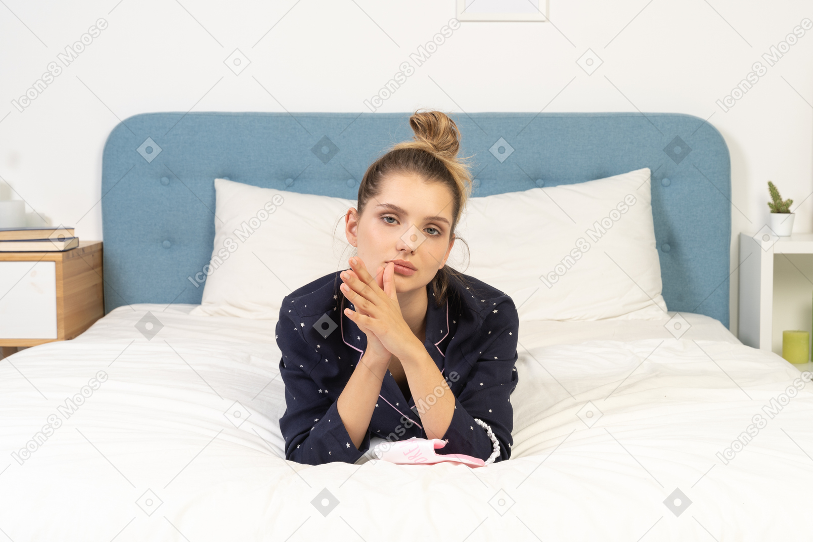 Front view of a bored young female laying in bed and holding hands together