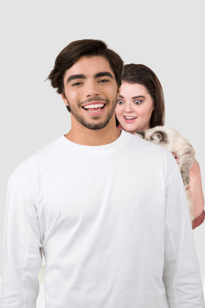 Woman with cat standing behind a smiling man