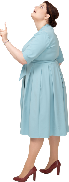 Vista lateral de uma mulher de vestido azul apontando para cima com um dedo