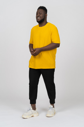 Vue de trois quarts d'un jeune homme à la peau foncée en t-shirt jaune se tenant la main