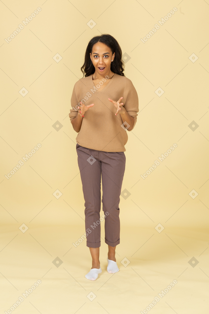 Vista frontal de una mujer joven sorprendida de piel oscura extendiendo sus dedos