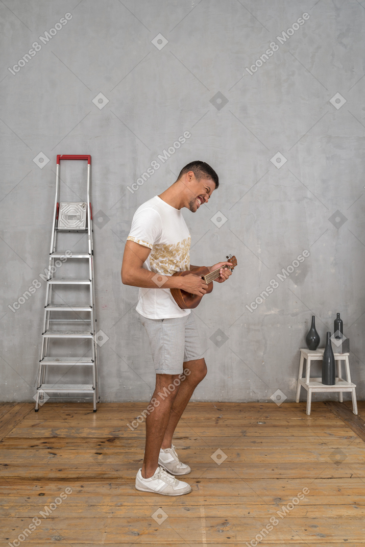 Side view of a man playing ukulele excitedly