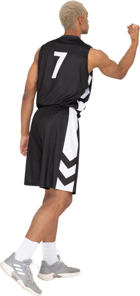 Dreiviertel-rückansicht eines jungen männlichen basketballspielers, der faust zeigt
