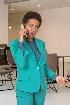 A woman in a turquoise suit talking on a cell phone