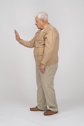 Vista lateral de um velho em roupas casuais, mostrando o gesto de parada