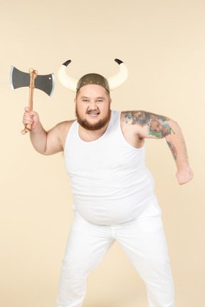 An emotional plus-sized man in white with a horned helmet on his head, holding a double-bladed axe