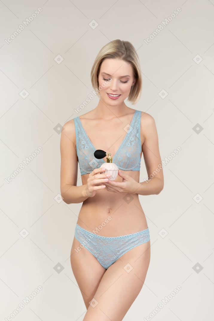 Young woman in lingerie holding perfume atomizer
