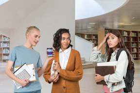 Three friends standing in study hall and one of them looking worried