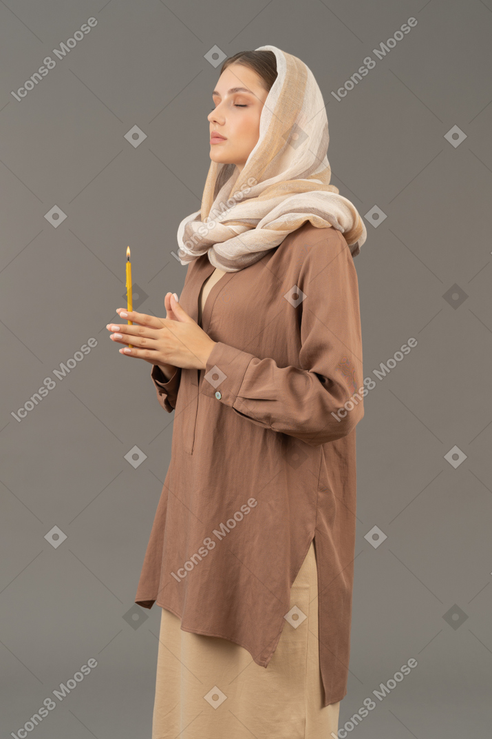 Religious woman holding a candle with her eyes closed
