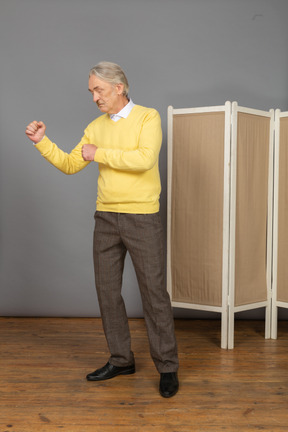 Three-quarter view of an old man clenching fists ready to defend