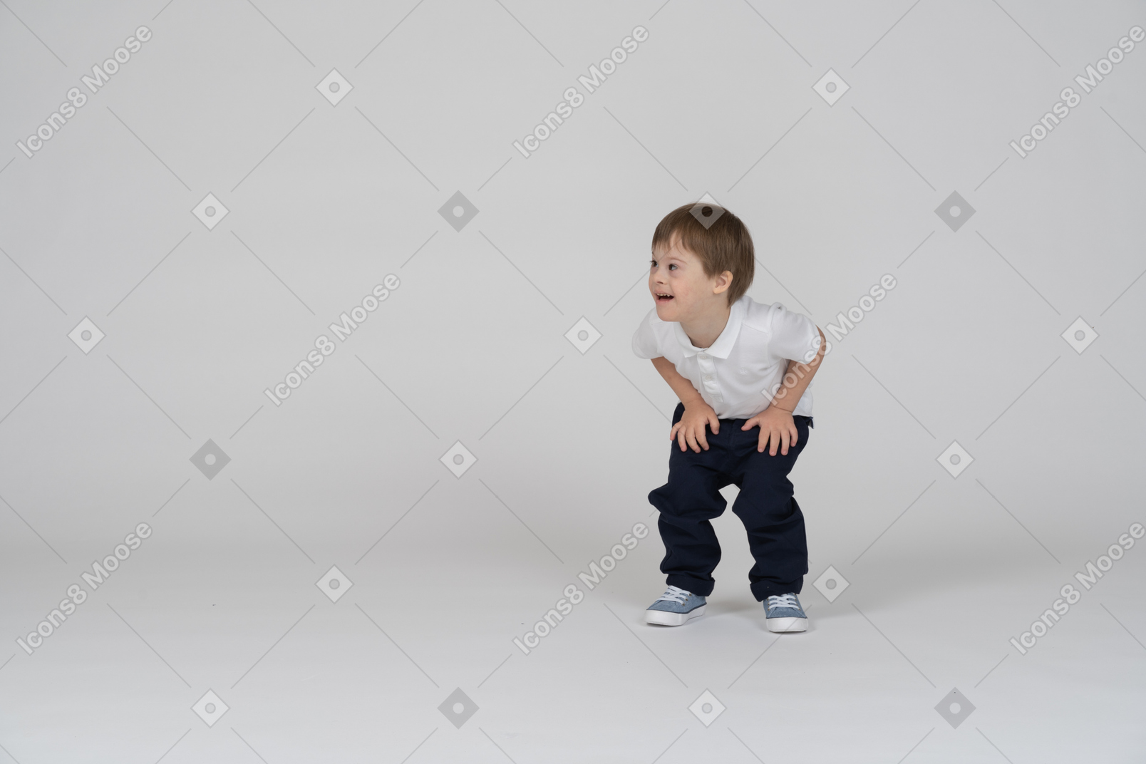 Vista frontal de um menino agachado e descansando as mãos nos joelhos