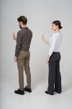 Vista de tres cuartos de una pareja joven en ropa de oficina extendiendo la mano