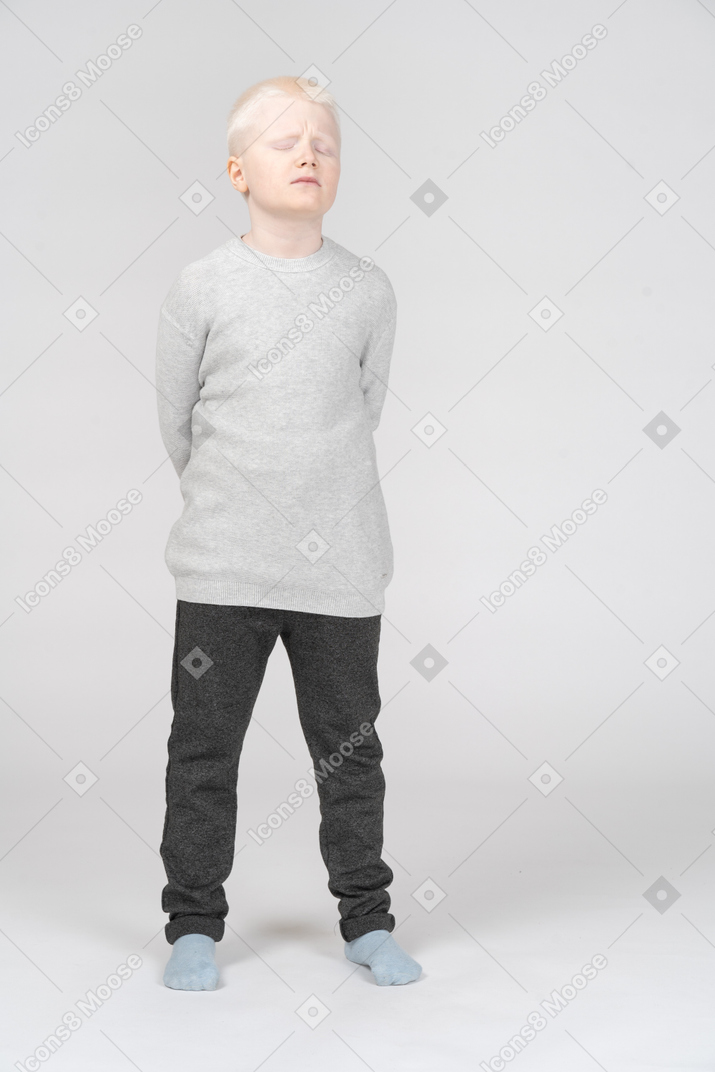 Front view of a blonde little boy in a bad mood