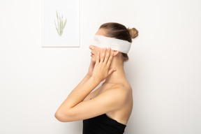 Woman with bandage over eyes holding face