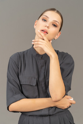 Front view of a young woman in a jumpsuit taking pill