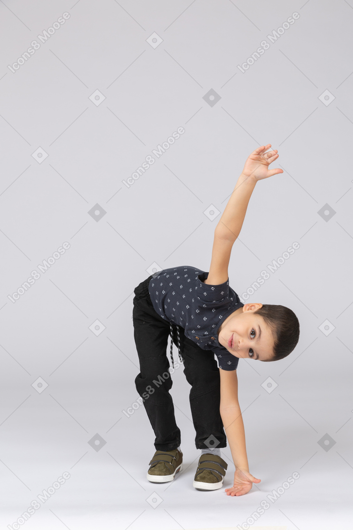 Vista frontal de um lindo garoto tocando o chão com a mão