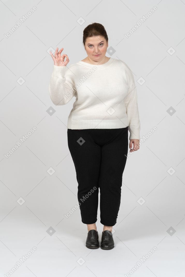 Женщина больших размеров в повседневной одежде показывает знак ок