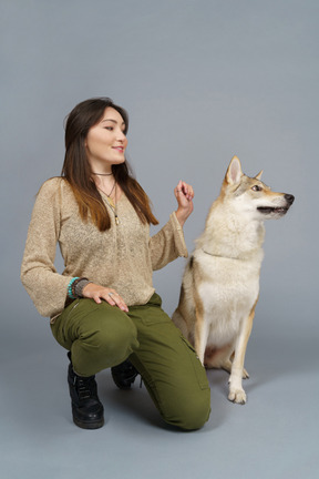 Figura intera di un maestro femminile sorridente seduto dal suo cane