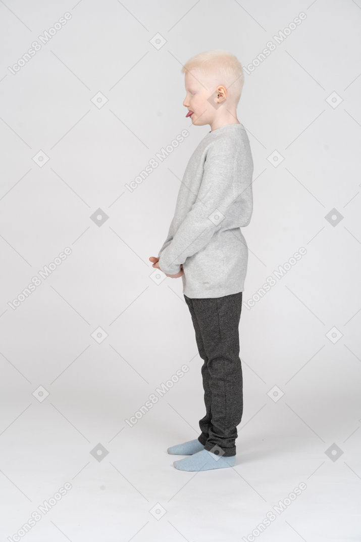 Side view of a kid boy in casual clothes showing tongue