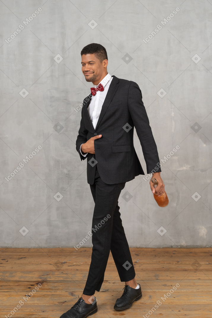 Smug-looking young man walking with a bottle in his hand