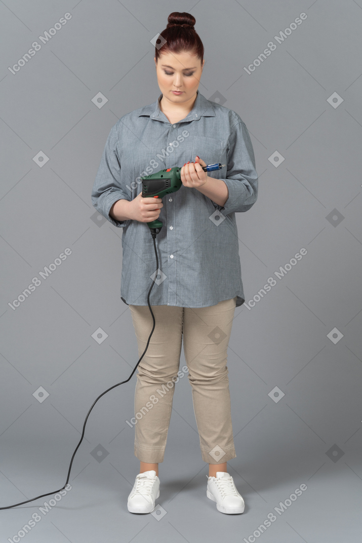 Young woman looking attentively at screw driver