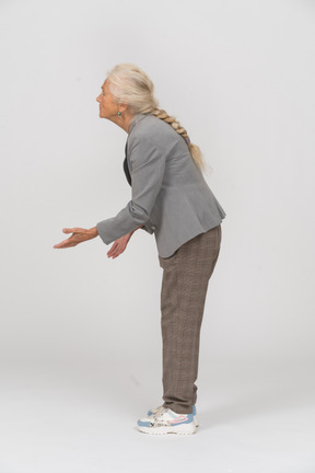 Vista lateral de uma senhora idosa de terno fazendo gesto de boas-vindas
