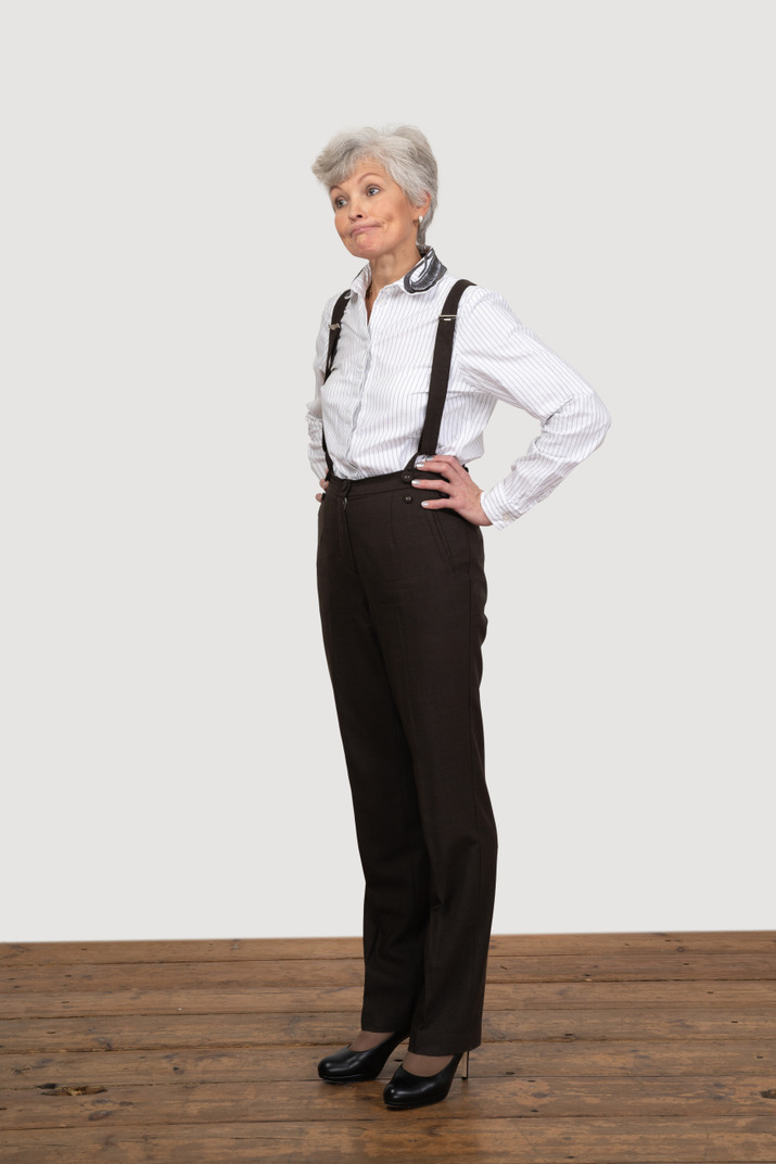 Three-quarter view of an old woman in office clothes putting hands on hips