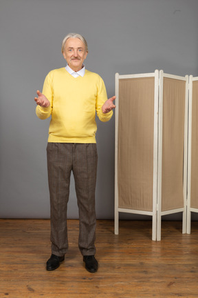 Front view of a smiling old man near the screen raising hands