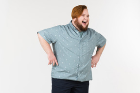Un uomo grassoccio in piedi con le mani sui fianchi e ridendo