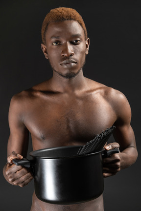Close-up a male holding a saucepan with pasta in it