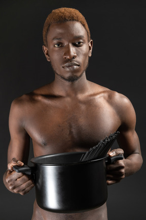 Close-up de um homem segurando uma panela com macarrão