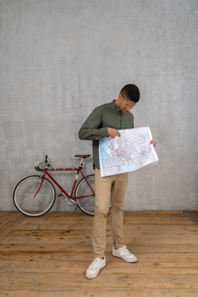 Three-quarter view of a man holding and pointing at a map