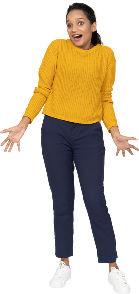 Front view of an emotional girl in casual clothes standing with outstretched arms and looking at camera