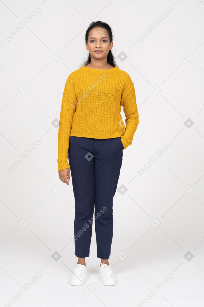 Front view of a girl in casual clothes standing with hand in pocket and looking at camera