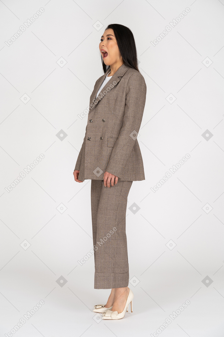 Dreiviertelansicht einer jungen dame im braunen business-anzug, die den mund öffnet