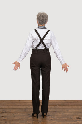 Back view of an old lady in office clothing outspreading her hands