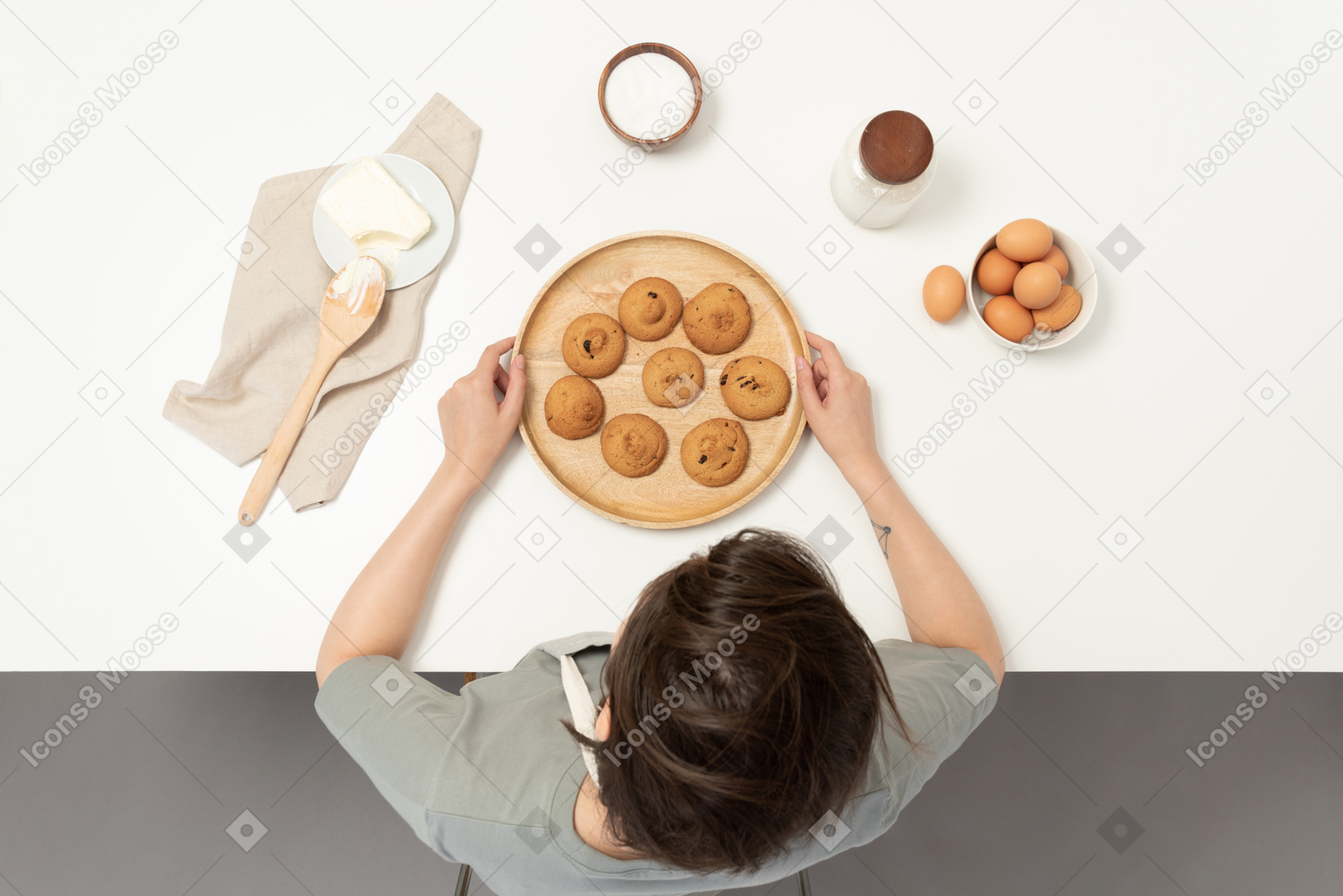 A female baker holding a plate of cookies
